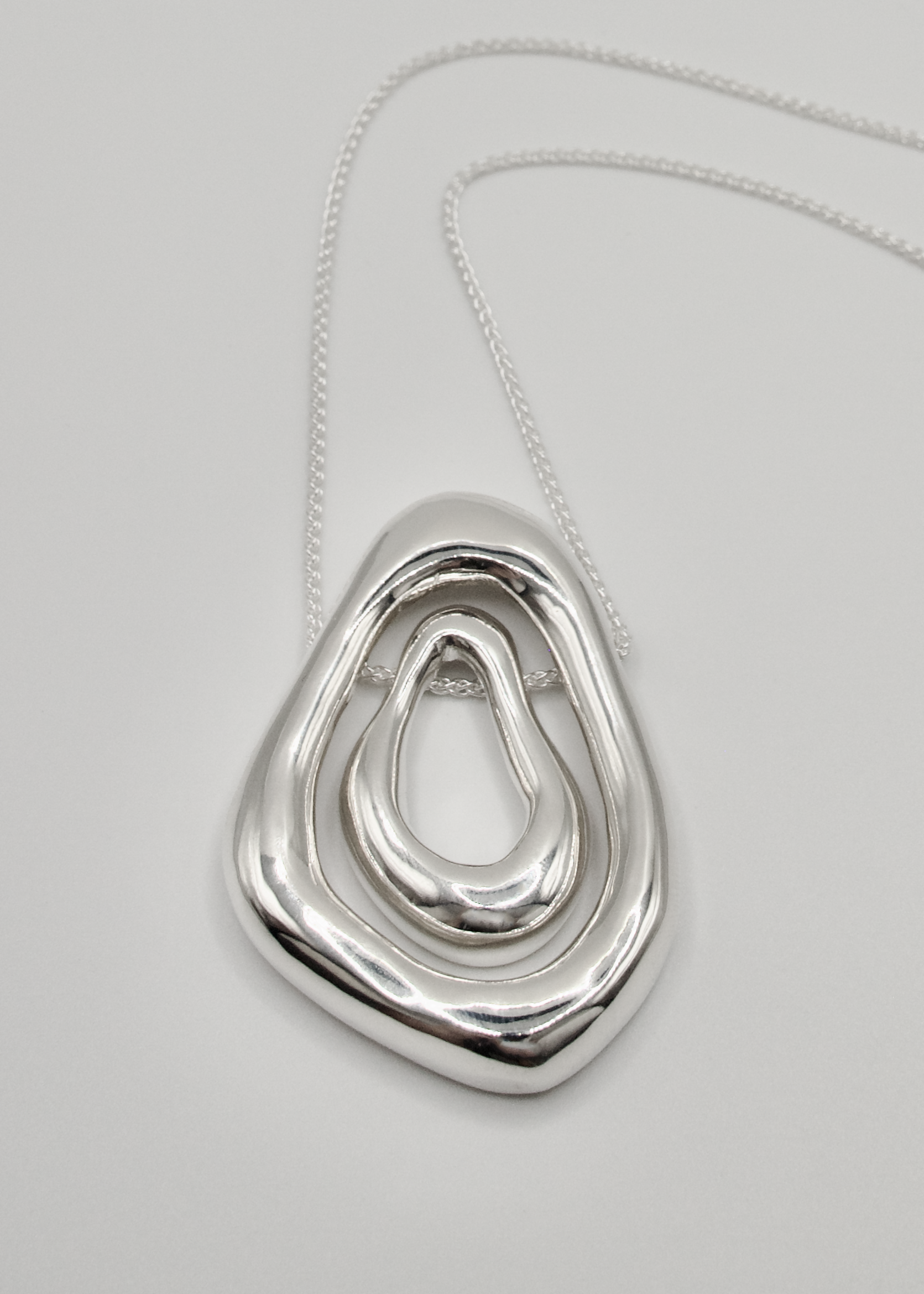The Andrea Pendant displayed in a minimalist studio setting, highlighting its versatile two-in-one design crafted from 925 sterling silver. This piece can be worn as a bold statement with both pendants or as a more understated accessory with just one.