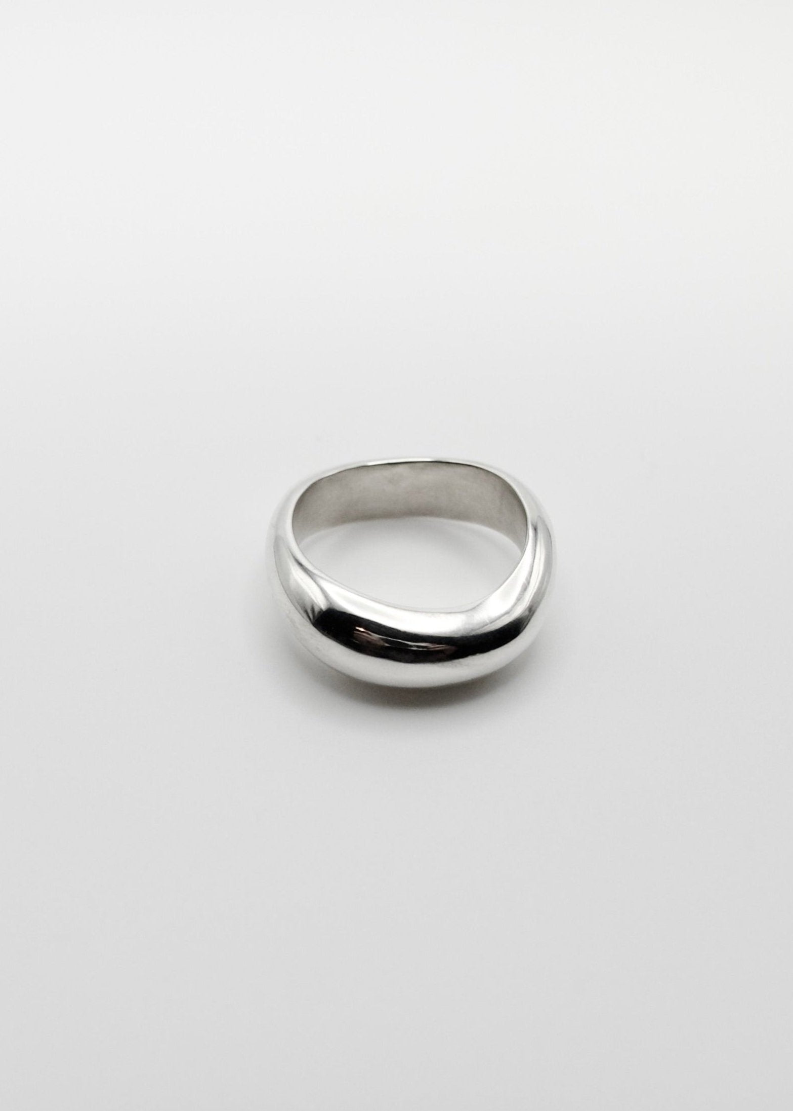 Anna Ring displayed on a neutral background, highlighting its organic wavy design and mirror-polished sterling silver finish.
