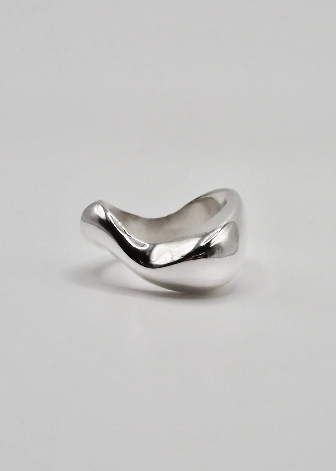 Clara Ring displayed on a neutral background, highlighting its organic, sculptural design and mirror-polished sterling silver finish.