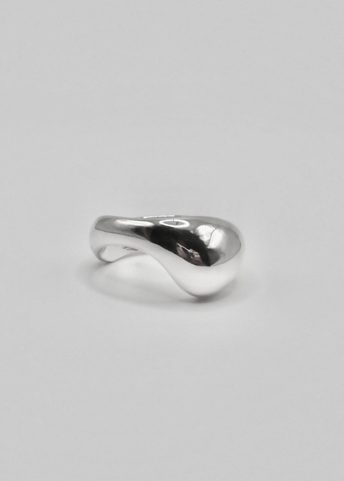 Ingrid Ring displayed on a neutral background, highlighting its flowing organic design and mirror-polished sterling silver finish.