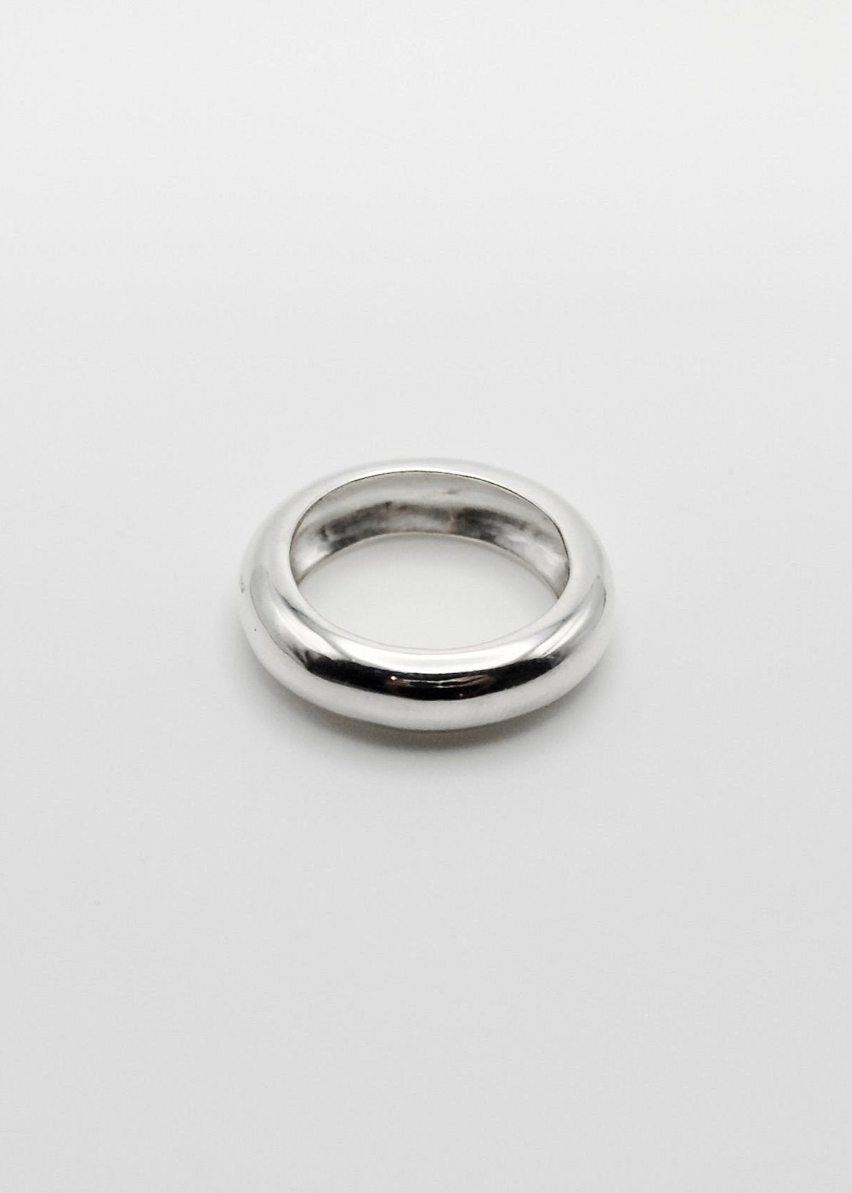 Jooni Ring displayed on a neutral background, highlighting its organic, round-shaped design and mirror-polished sterling silver finish.