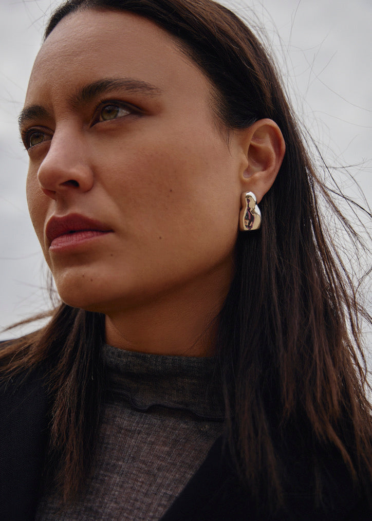 Close up of the model wearing the Luna earrings their graceful organic shape and how they complement various styles and also the shine from the mirror polishing.
