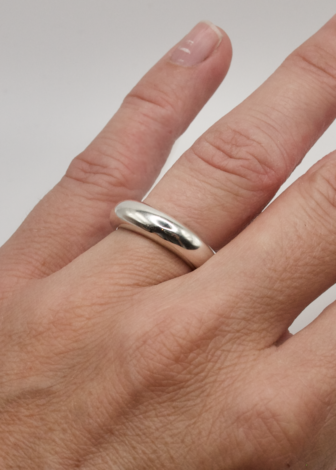 Detailed view of the Jooni Ring on the finger close up, focusing on its 5mm width and the reflective quality of the 925 sterling silver.