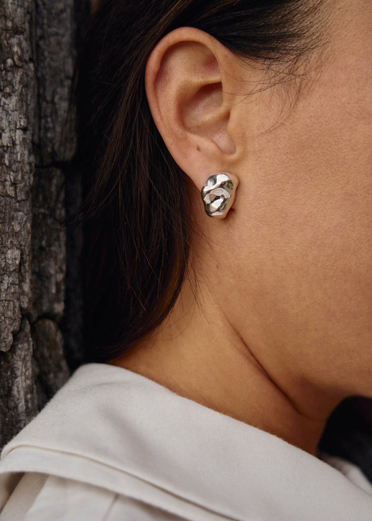 The Gaia Earrings worn by a model, highlighting their sleek, reflective design and how they complement modern, everyday outfits with a touch of sophistication.