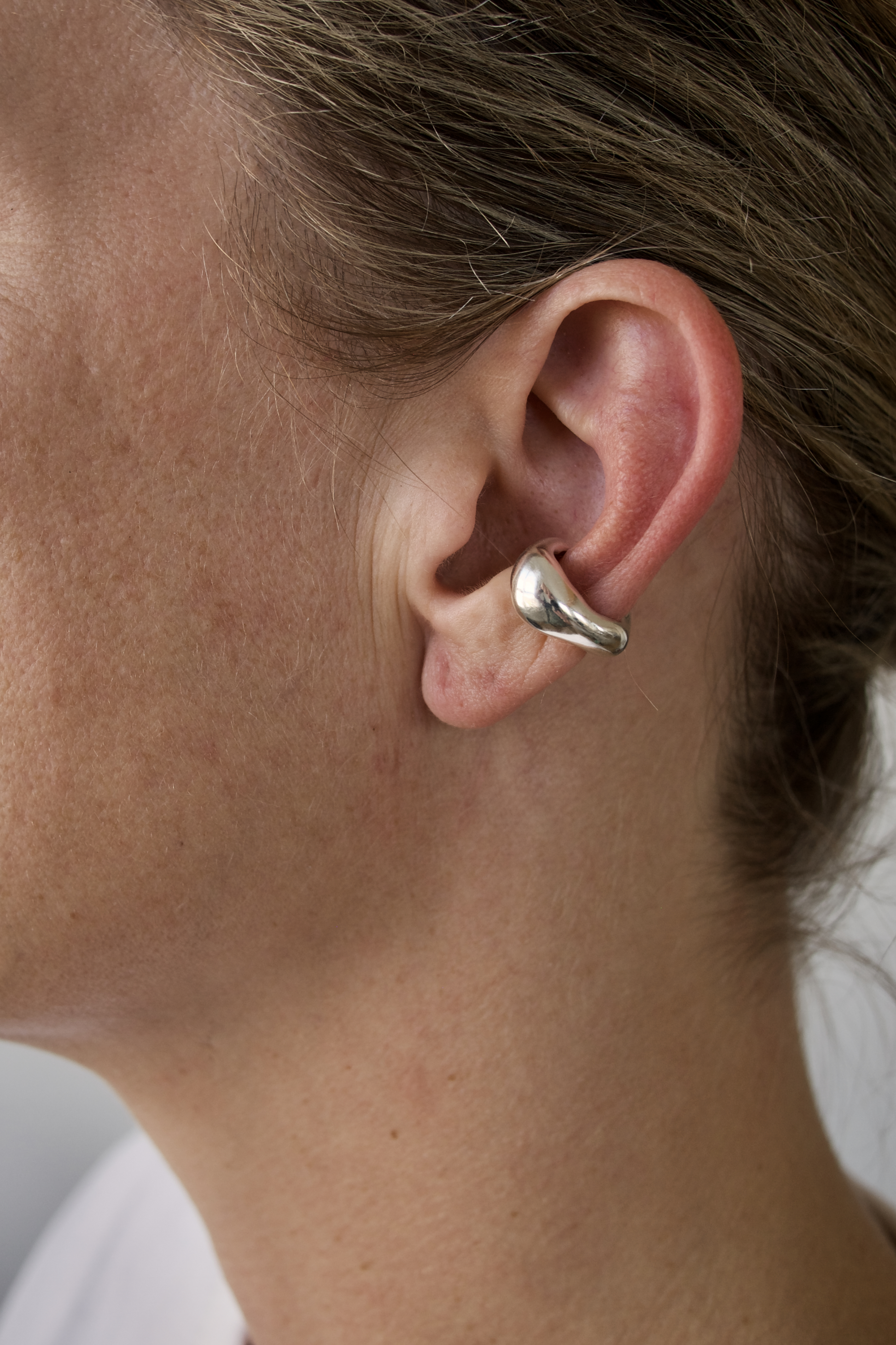 Close-up of an earcuff in sterling silver with a white background