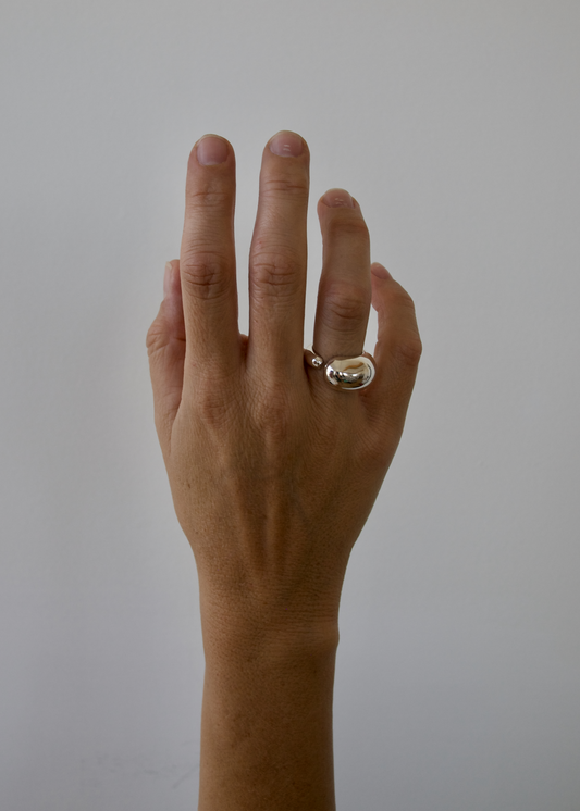 Hand wearing a ring on a plain background