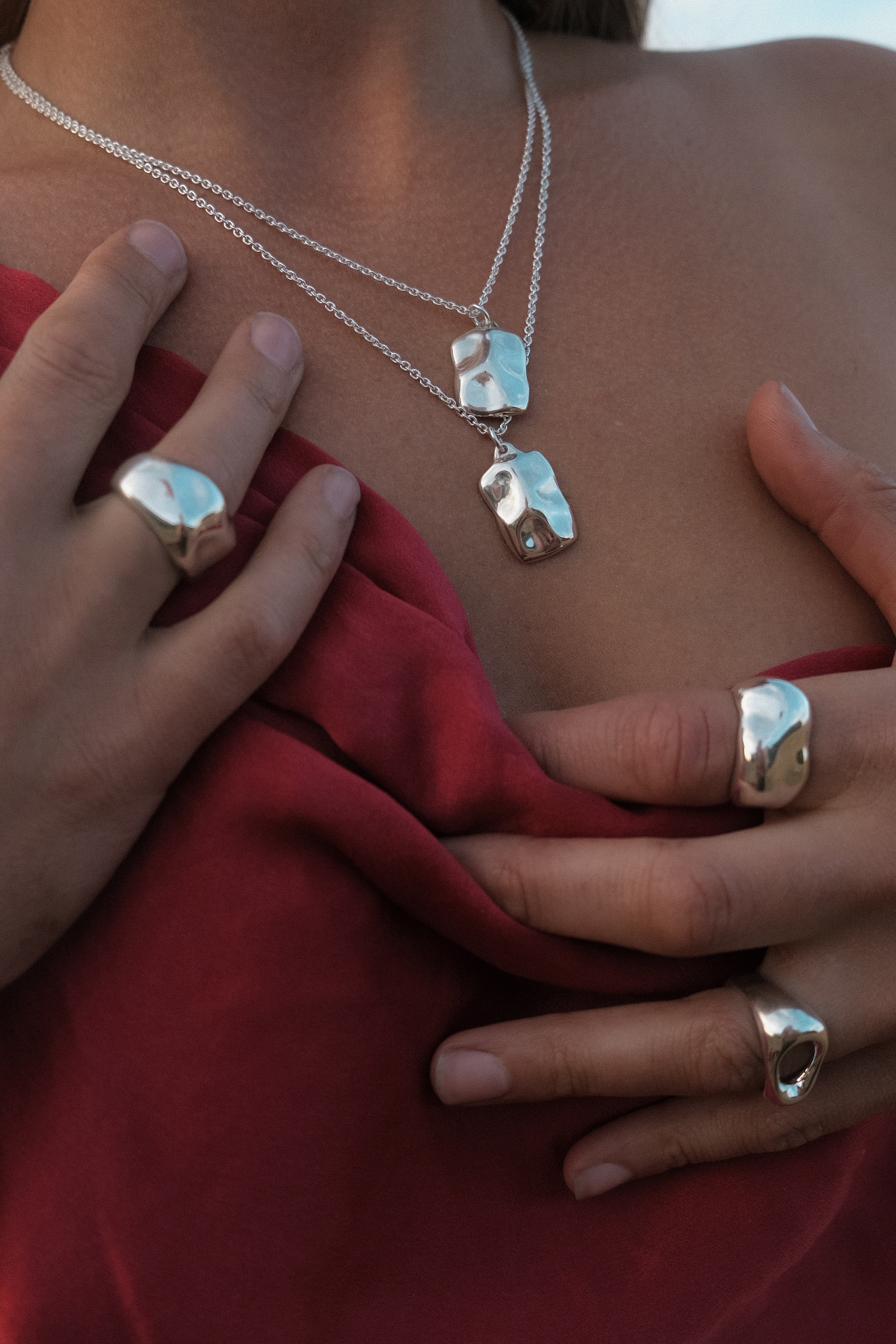 Close-up of a person wearing silver jewelry with a red garment all jewellery being organic and sculptured in sterling silver from SEOLA atelier