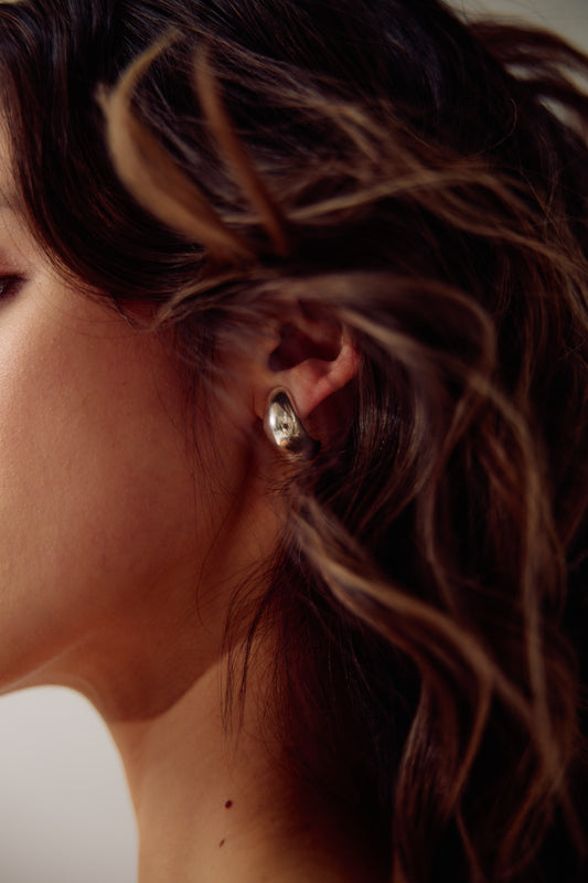 Model wearing the Sigrid hand made hoop earrings, in sculptured sterling silver from Seola Atelier