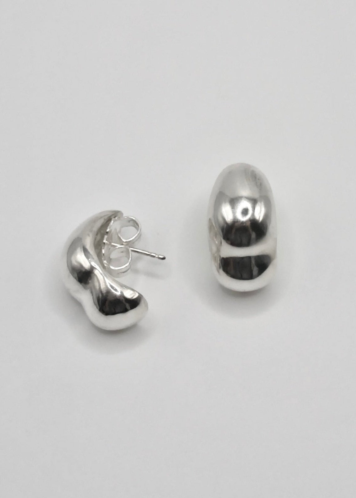 Sigrid Earrings displayed on a neutral background, highlighting their organic, curved design and mirror-polished sterling silver finish.