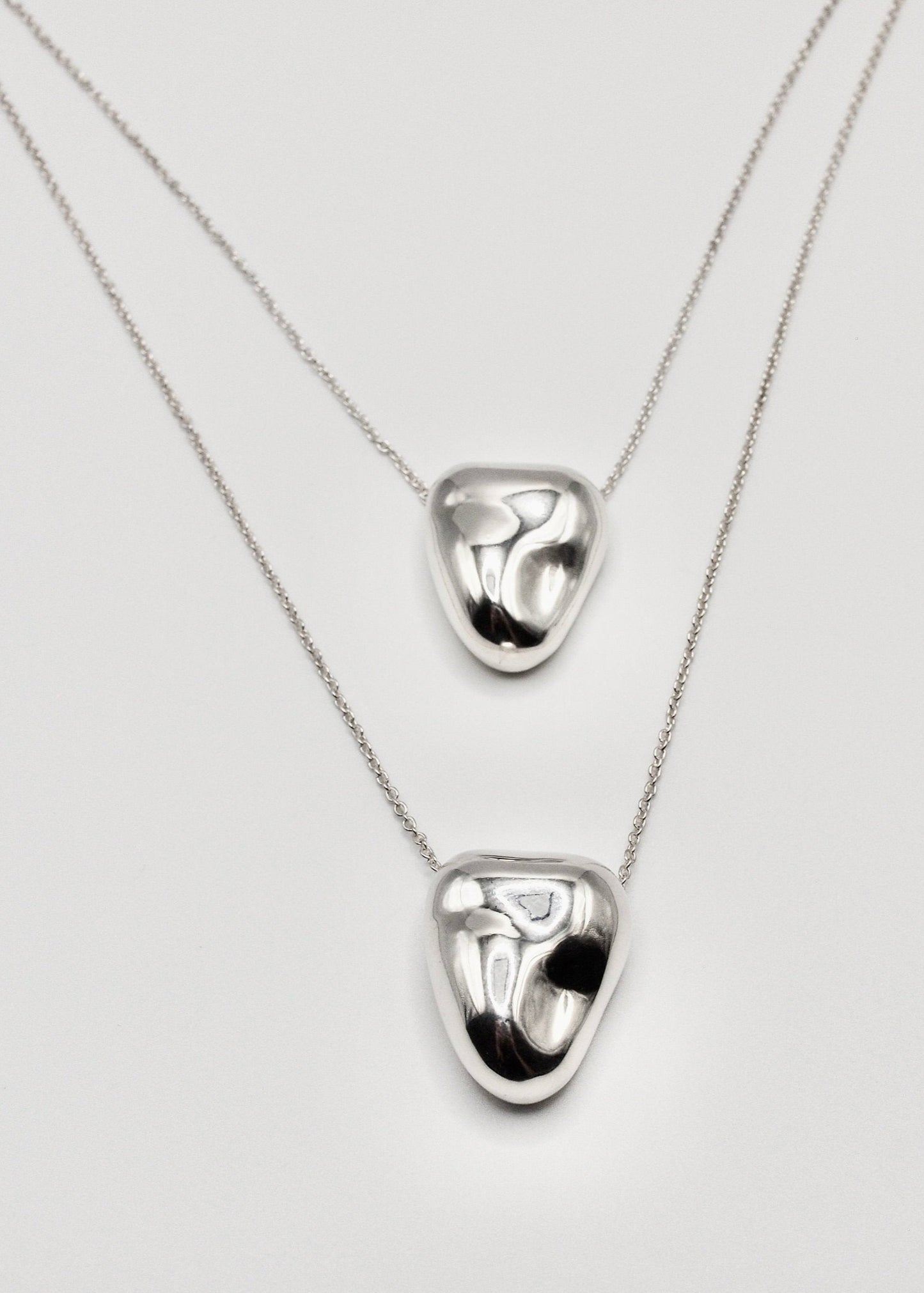 Two Heart Pendant displayed on a neutral background, highlighting its organic shape and mirror-polished sterling silver finish.