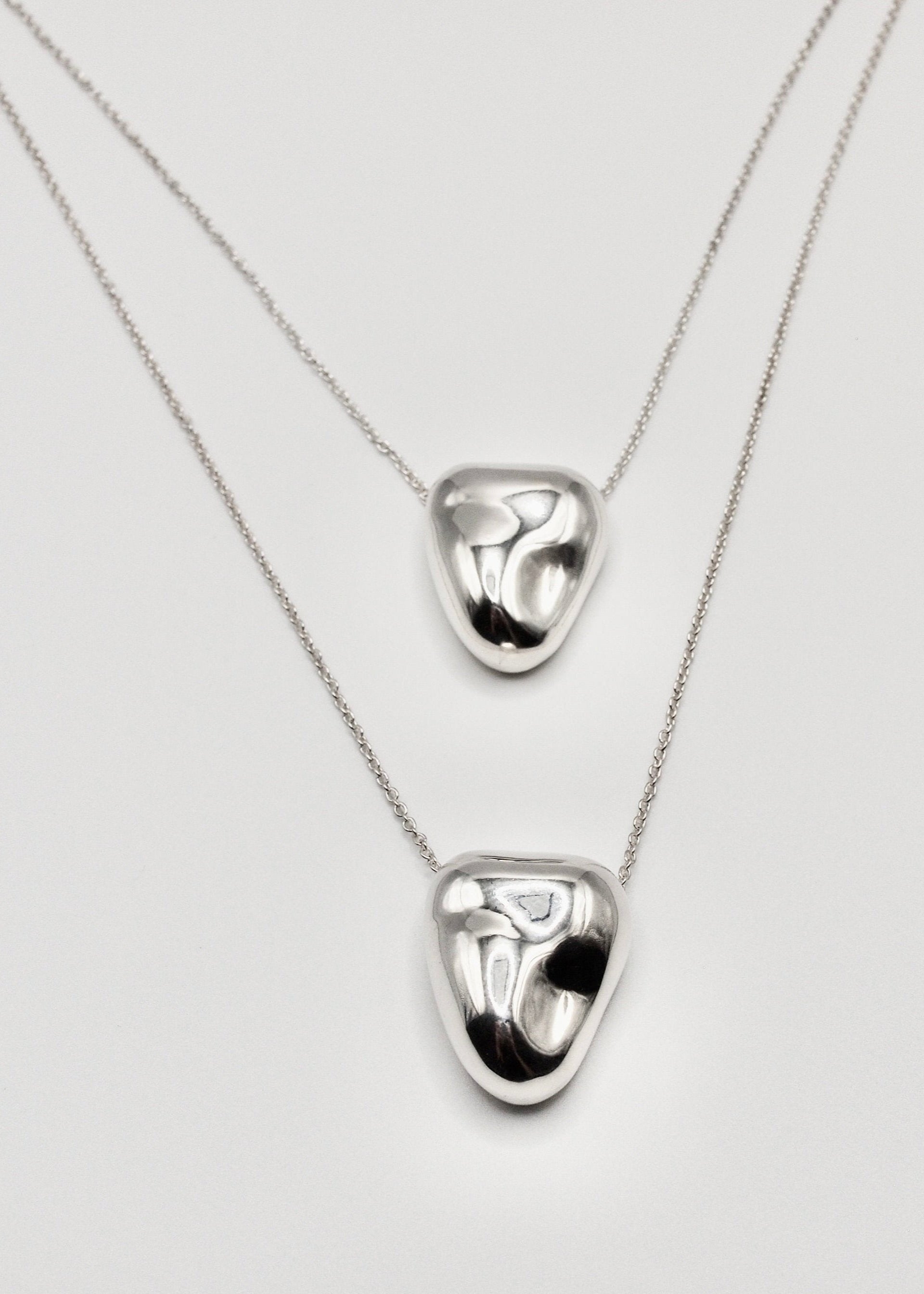 Two Heart Pendant displayed on a neutral background, highlighting its organic shape and mirror-polished sterling silver finish.