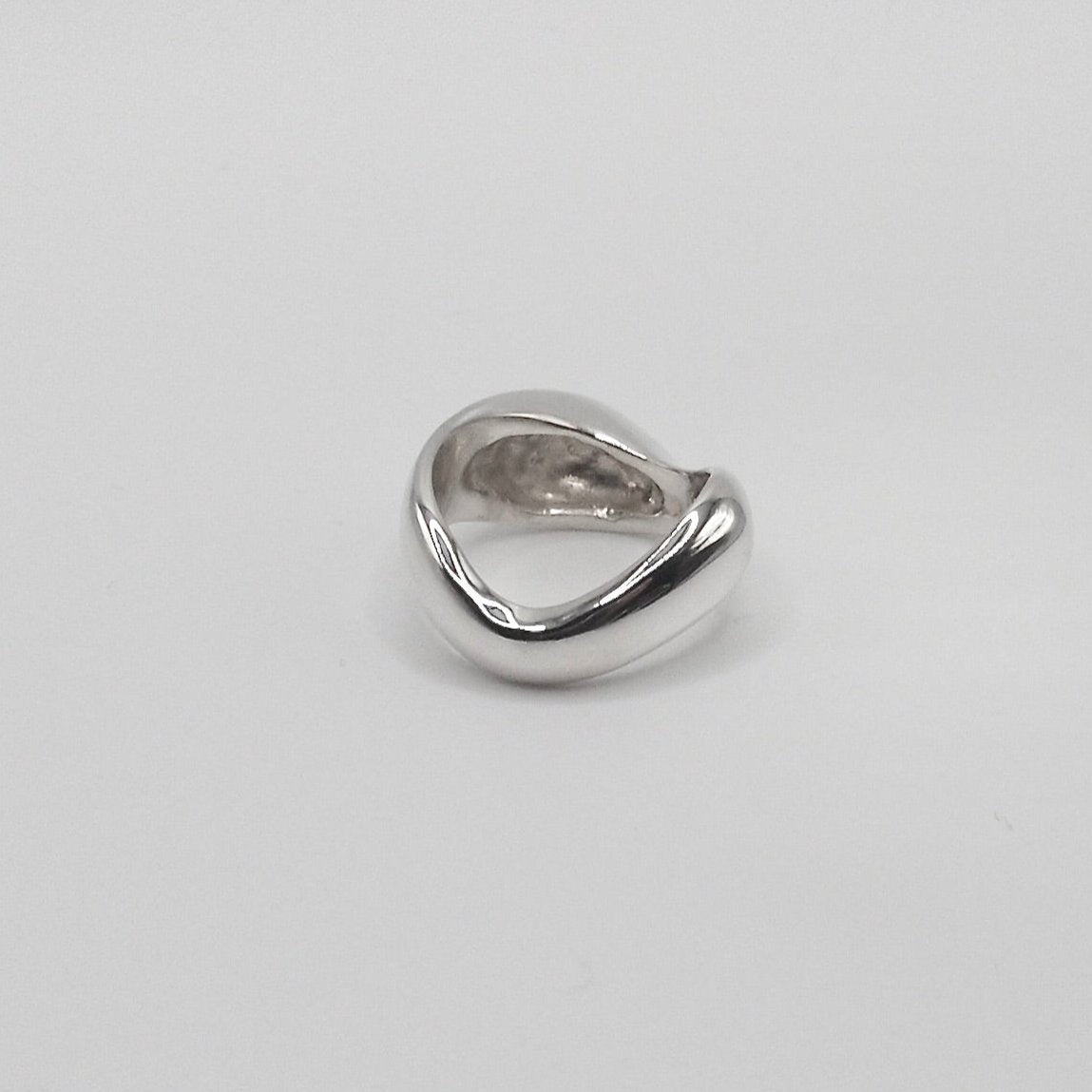 Detailed view of the Ingrid Ring, focusing on its intricate craftsmanship and the reflective quality of the 925 sterling silver. The ring is photogrpahed from the back to show the sculptured curves 