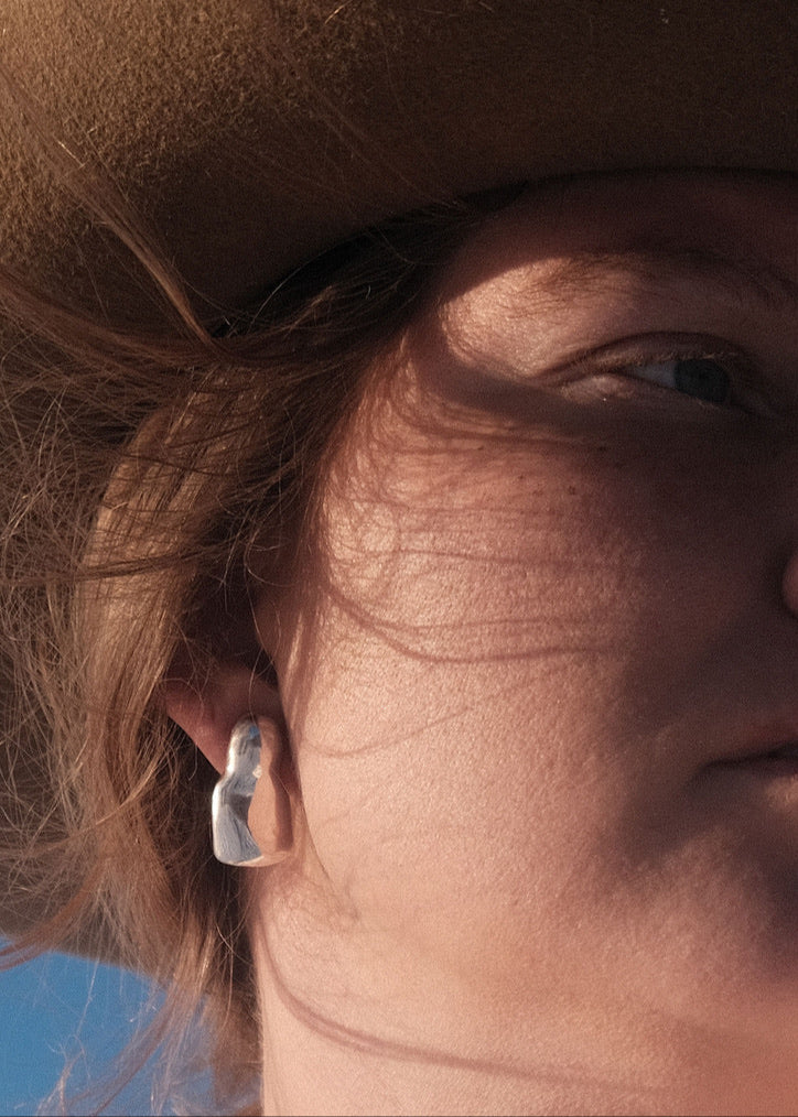 Close-up of a model wearing the Luna Earrings, emphasizing their graceful movement and how they complement various styles. The Luna Earrings are a testament to minimalist elegance